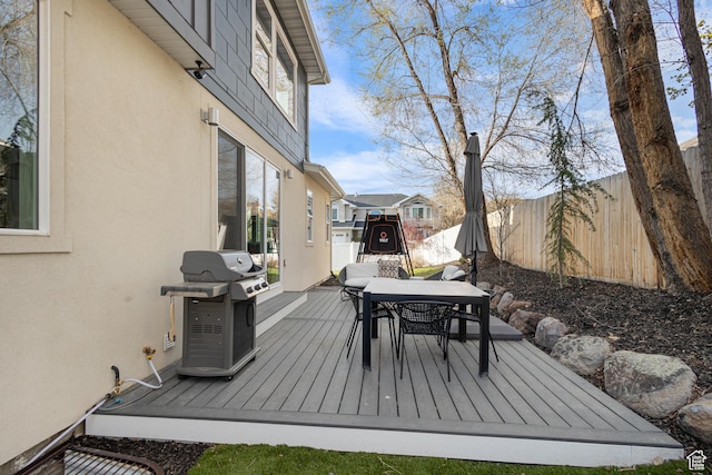 wooden deck with grilling area, outdoor dining space, and fence