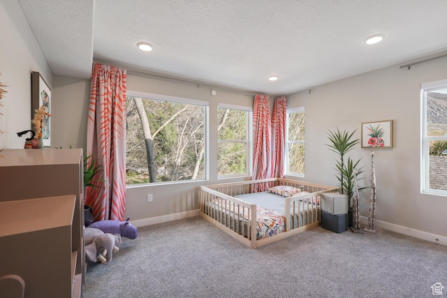 carpeted bedroom with recessed lighting, baseboards, and a textured ceiling