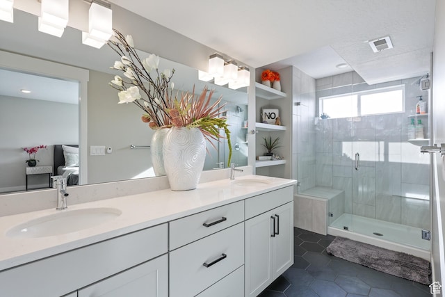 ensuite bathroom featuring a sink, visible vents, double vanity, and a stall shower