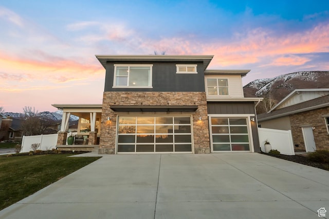 view of front of house featuring a garage, stone siding, and concrete driveway