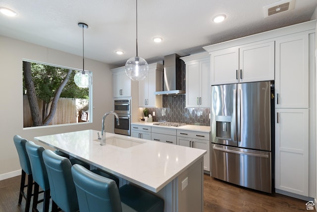 11779 S Windcroft Ct E, Sandy, UT 84092 - kitchen with stainless steel appliances, wall chimney range hood, a sink, a center island with sink, and tasteful backsplash