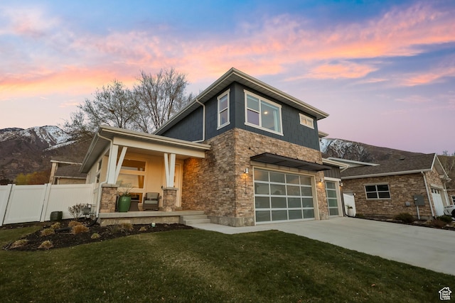view of front of property featuring a yard, covered porch, stone siding, fence, and concrete driveway