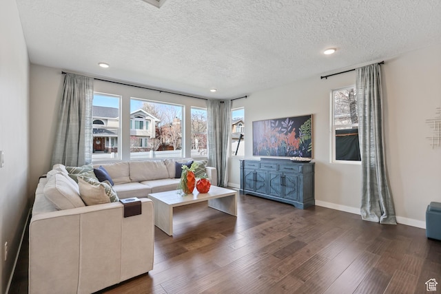 living area with a textured ceiling, baseboards, and dark wood finished floors
