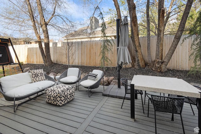 wooden terrace featuring outdoor dining space and a fenced backyard