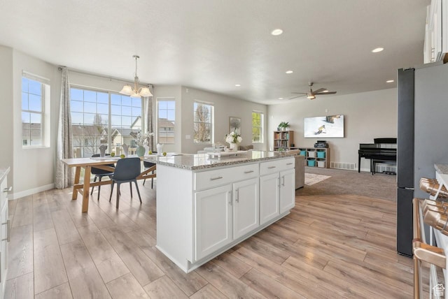 kitchen with white cabinets, a center island, light wood-type flooring, and freestanding refrigerator