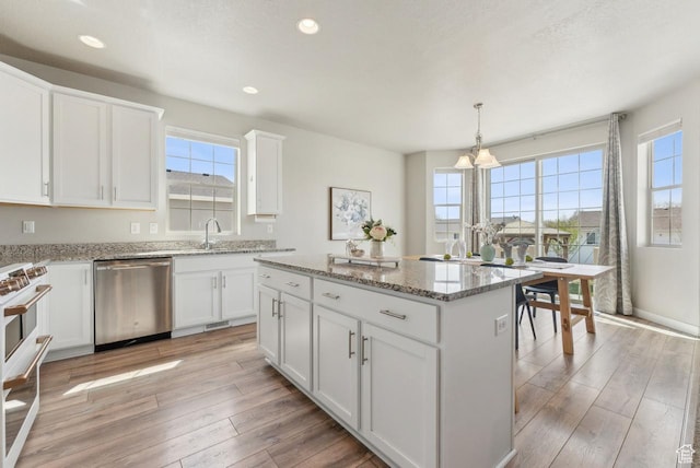 kitchen featuring a wealth of natural light, light wood-type flooring, stainless steel dishwasher, range, and a kitchen island