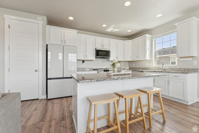kitchen with light wood-type flooring, refrigerator, and white cabinetry