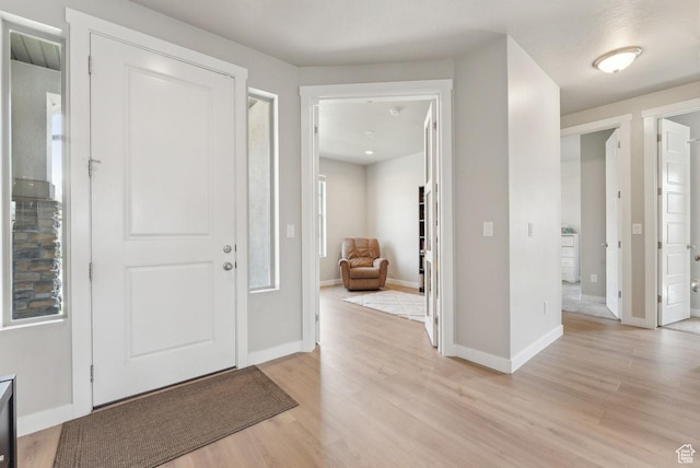 foyer with light wood-style floors and baseboards