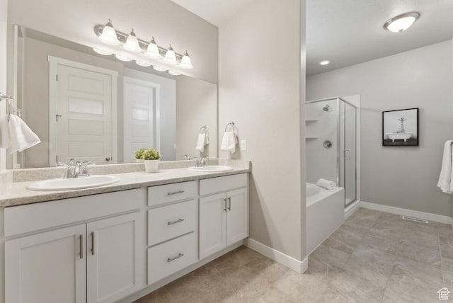 full bath featuring a shower stall, double vanity, a sink, and baseboards