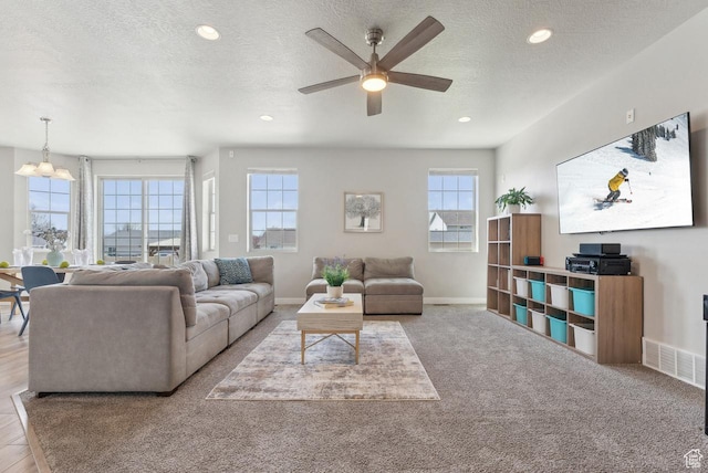 living room with baseboards, recessed lighting, ceiling fan with notable chandelier, and a textured ceiling