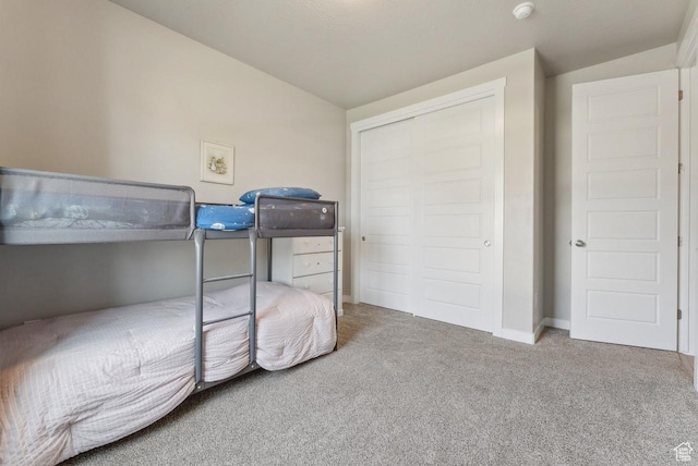 carpeted bedroom featuring baseboards, a closet, and vaulted ceiling