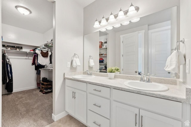 full bathroom with a walk in closet, double vanity, and a sink