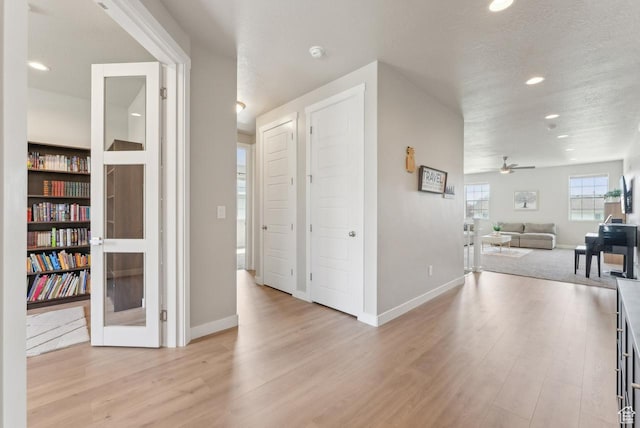 hall featuring recessed lighting, baseboards, a textured ceiling, and wood finished floors