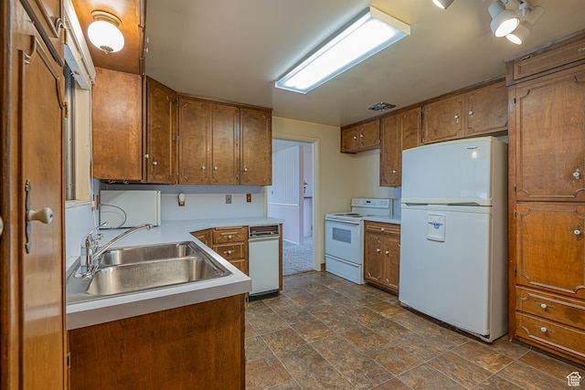 kitchen featuring a sink, light countertops, brown cabinetry, and white appliances