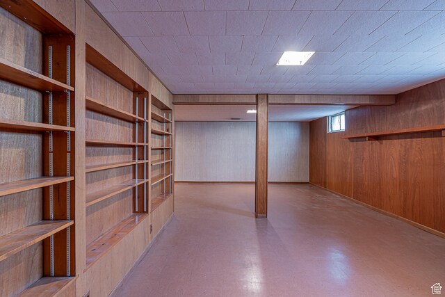 below grade area with tile patterned floors, wooden walls, and built in features