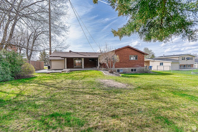 back of house featuring brick siding, fence, a garage, and a lawn