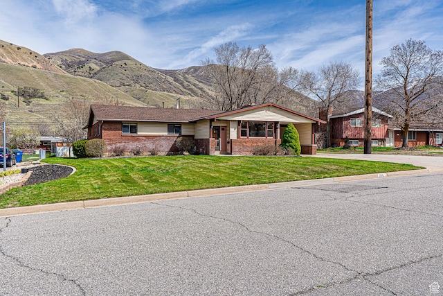 view of front facade with brick siding, a front yard, and a mountain view