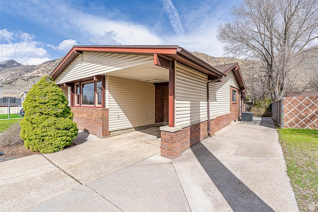 view of front facade with concrete driveway, a carport, a mountain view, brick siding, and central AC