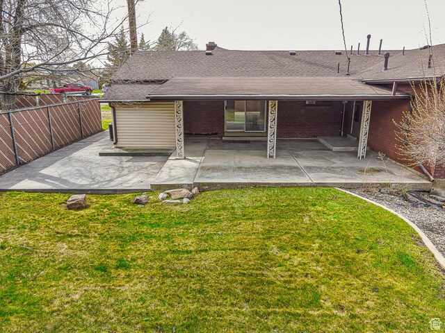 back of house featuring a patio, a yard, a shingled roof, and fence