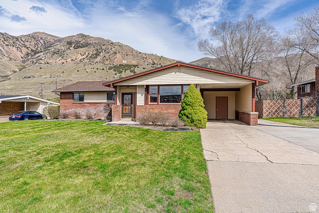 view of front of house with a carport, a front yard, fence, brick siding, and driveway