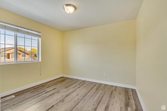 unfurnished room with wood finished floors, baseboards, and visible vents