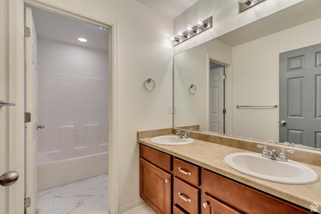bathroom with double vanity, marble finish floor, a sink, and washtub / shower combination