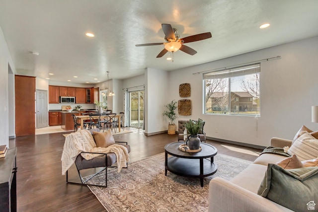 living room with dark wood-type flooring, baseboards, a ceiling fan, and recessed lighting