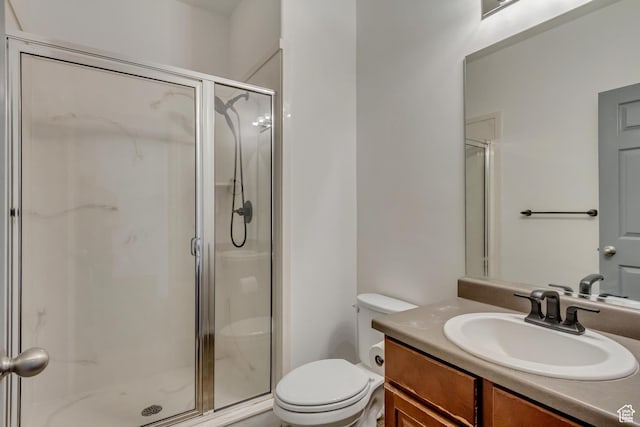 bathroom with toilet, a stall shower, and vanity