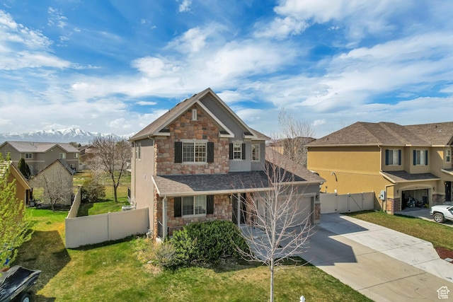 view of front of home featuring concrete driveway, stone siding, an attached garage, a front yard, and fence
