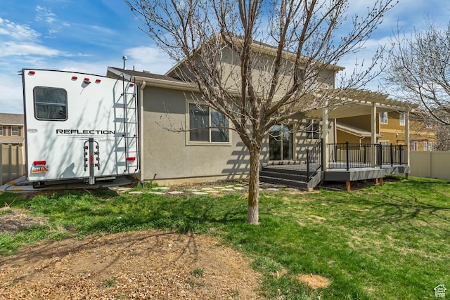 rear view of house featuring a pergola, a lawn, fence, stucco siding, and a wooden deck