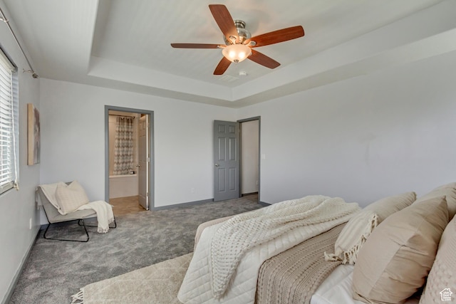 bedroom featuring baseboards, a raised ceiling, ceiling fan, carpet, and connected bathroom