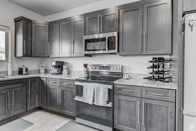129 W Autumn Ln N, Saratoga Springs, UT 84045 - kitchen with appliances with stainless steel finishes, light stone countertops, and light wood finished floors