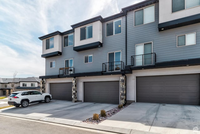 129 W Autumn Ln N, Saratoga Springs, UT 84045 - view of front of home featuring an attached garage, driveway, a balcony, and stucco siding