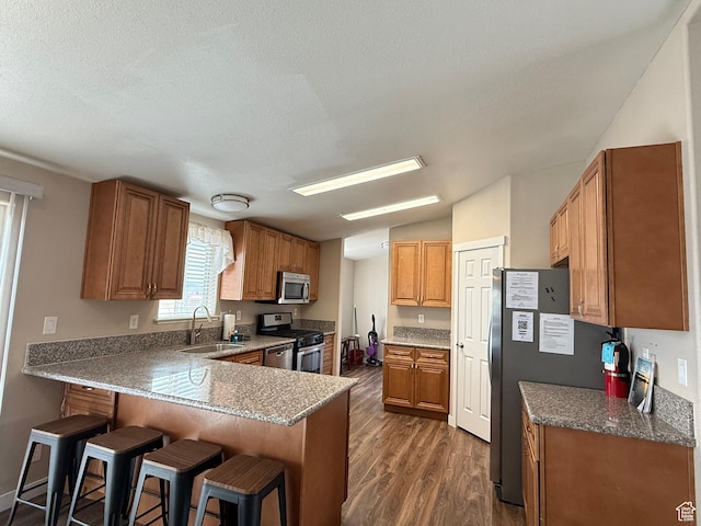 288 W Stuart Dr, Garden City, UT 84028 - kitchen with a kitchen breakfast bar, dark wood-type flooring, a peninsula, a sink, and stainless steel appliances