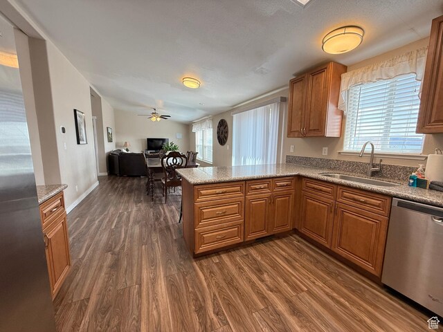 288 W Stuart Dr, Garden City, UT 84028 - kitchen with dark wood-style flooring, a peninsula, brown cabinets, appliances with stainless steel finishes, and a sink
