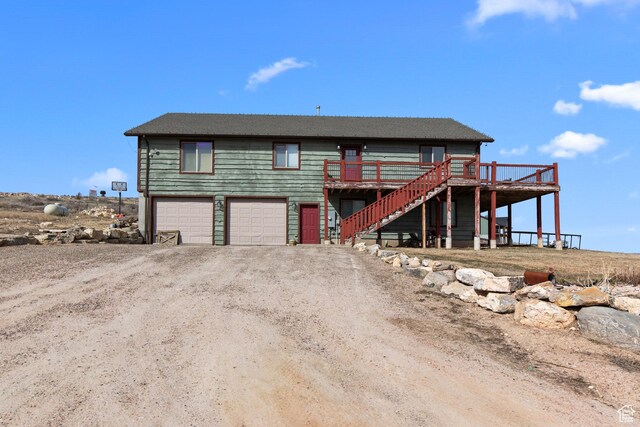 671 W Dee Dr, Garden City, UT 84028 - view of front of house featuring dirt driveway, an attached garage, a wooden deck, and stairs