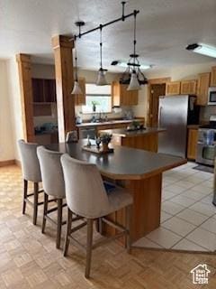 87 N Loafer Canyon Rd, Elk Ridge, UT 84651 - kitchen with a kitchen bar, brown cabinets, dark countertops, and stainless steel appliances