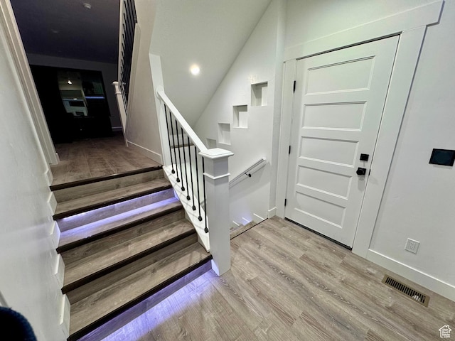 stairs with visible vents, baseboards, and wood finished floors