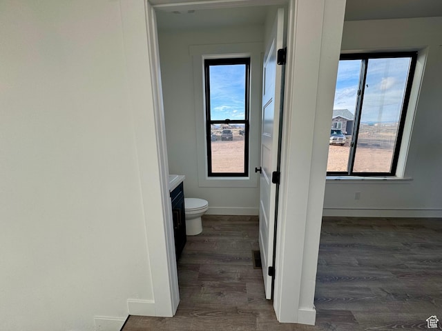 bathroom featuring toilet, wood finished floors, vanity, and baseboards