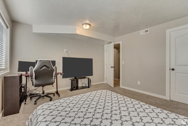 home office with a textured ceiling, light colored carpet, baseboards, and visible vents