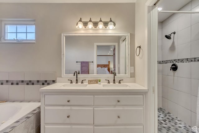 bathroom with tiled shower, double vanity, a sink, and ensuite bath