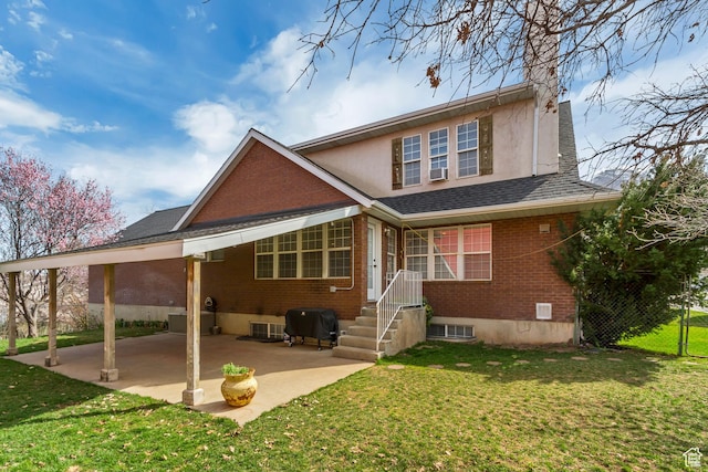 back of property featuring a patio, an attached carport, brick siding, a shingled roof, and a lawn