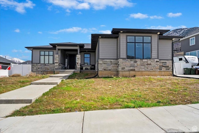 prairie-style house featuring a front yard and stone siding