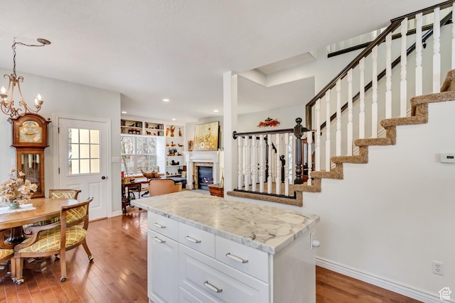 3895 S Grindstone Dr, Springville, UT 84663 - kitchen with light wood finished floors, a fireplace, white cabinetry, and baseboards