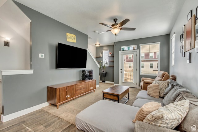 living area with light wood finished floors, baseboards, and a ceiling fan