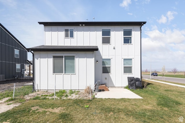 rear view of property with board and batten siding, cooling unit, a yard, and a patio