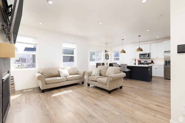 living area with recessed lighting, light wood-type flooring, and baseboards