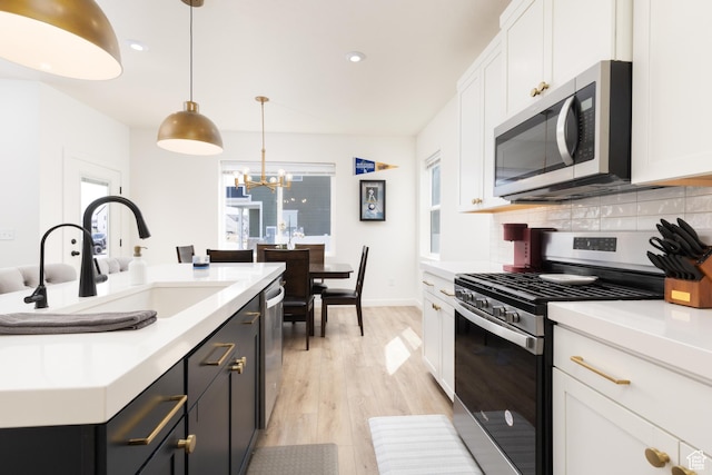 kitchen featuring light countertops, white cabinetry, decorative backsplash, stainless steel appliances, and a sink