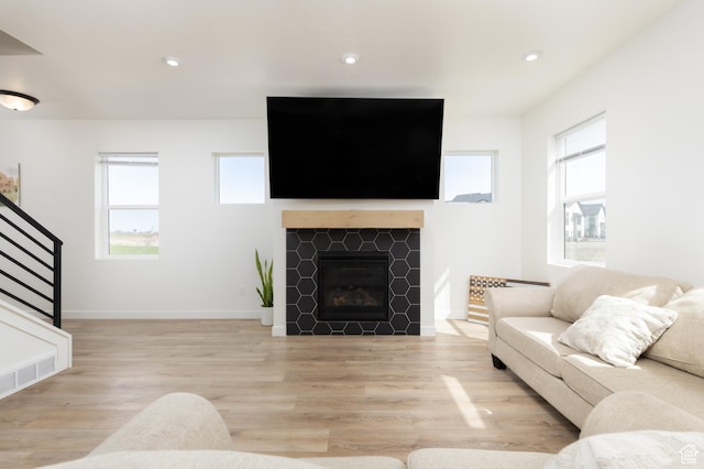 living area with light wood-type flooring, plenty of natural light, recessed lighting, and stairs