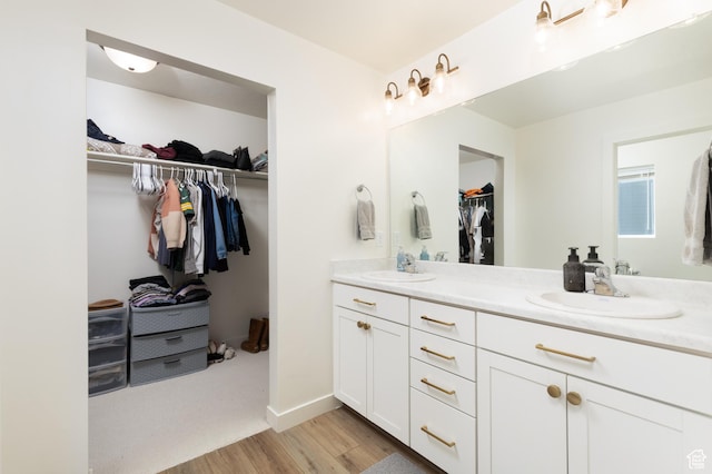 bathroom with a sink, baseboards, double vanity, and wood finished floors